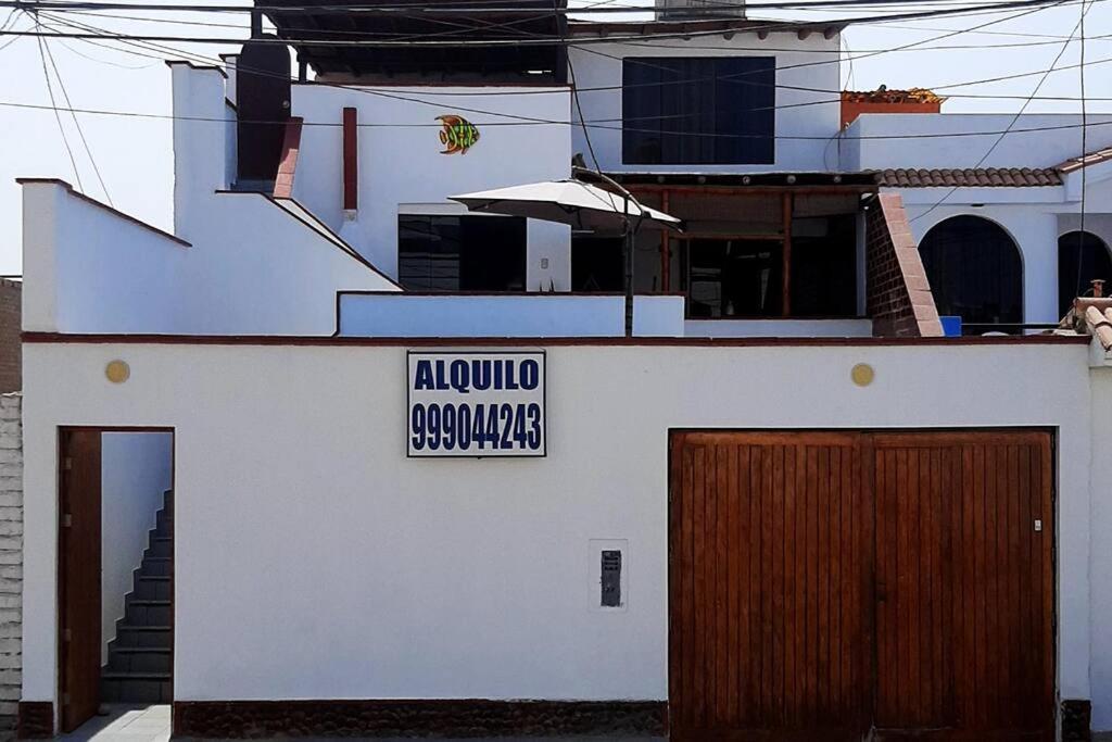 Una casa blanca con un cartel en el costado. en Lindo departamento en Punta Hermosa, en Punta Hermosa