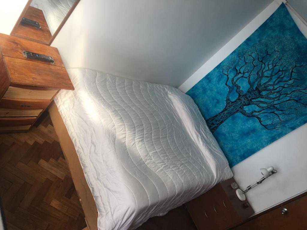 a bed in a room with a tree on the wall at Casa Hostal Vista al Mar in Valparaíso