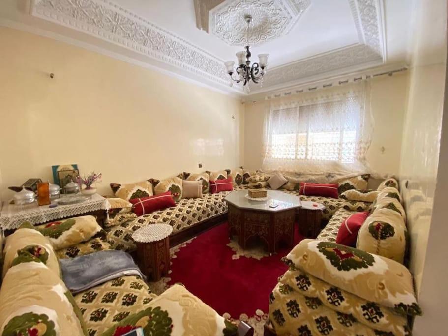 uma ampla sala de estar com sofás e um lustre em Grande maison Calme em Meknès