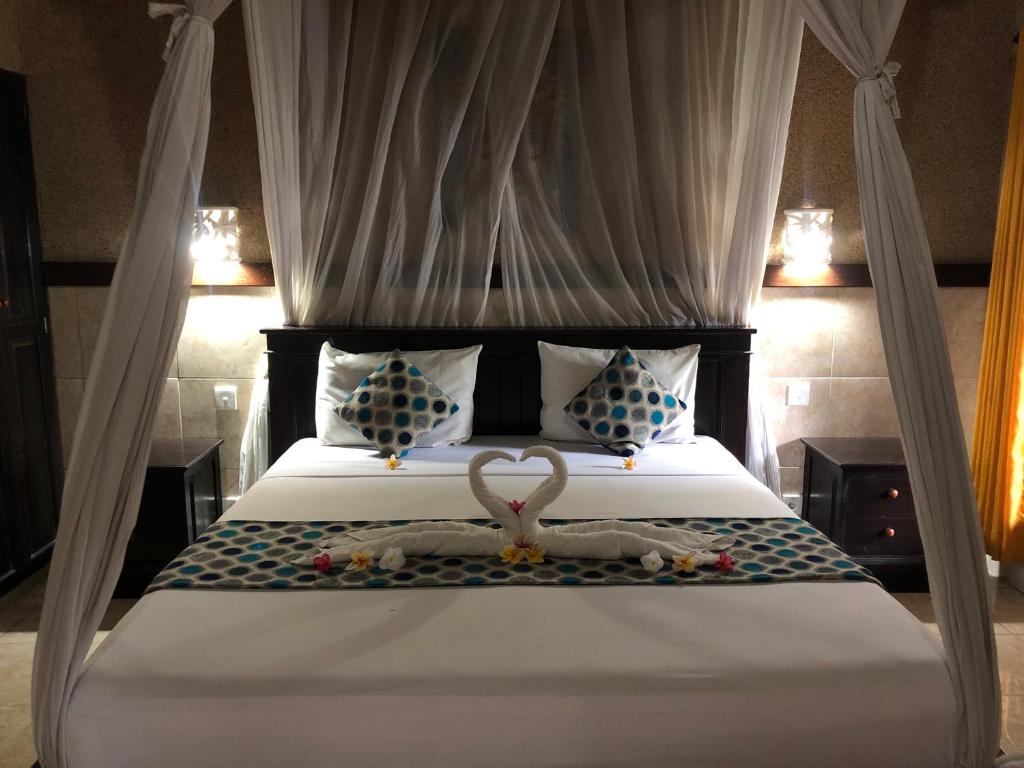 - une chambre avec un lit recouvert d'un cygne dans l'établissement Pondok Shindu Guest House, à Pemuteran