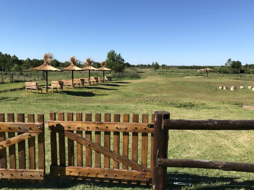 a wooden fence with many tables and umbrellas in a field at El Nopal - Alojamiento in San Pedro