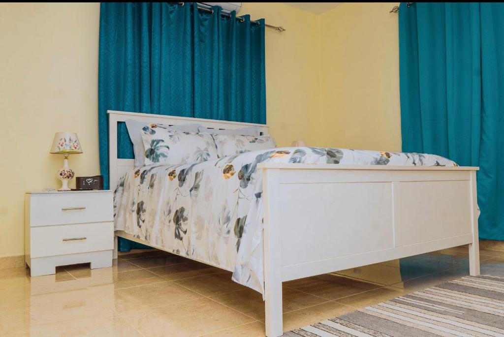 a bedroom with a white bed and blue curtains at A-1 Hermoso Apartamento tipo villa al pie de la montaña elitevillasjarabacoa in Jarabacoa