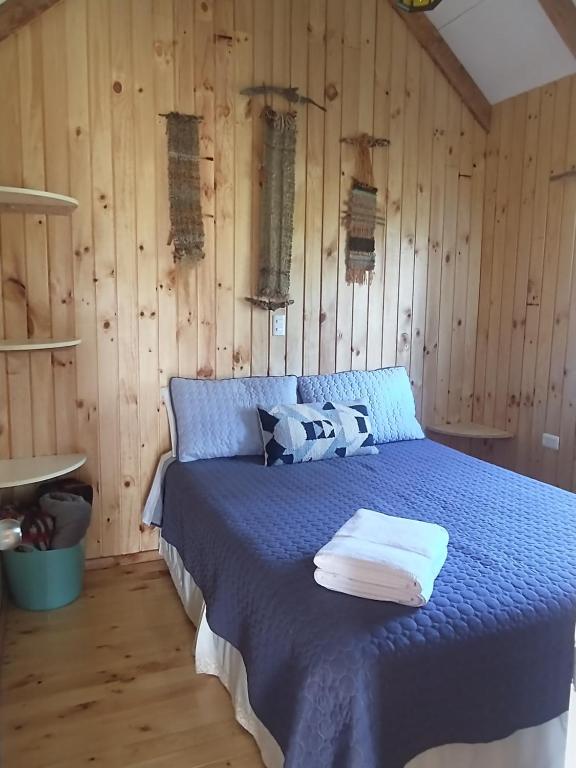 - une chambre avec un lit bleu et des murs en bois dans l'établissement Cabañas Sotobosque, à Puelo