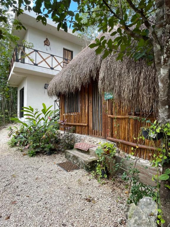a house with a thatch roof and a fence at Aldea Yuyu in Tulum