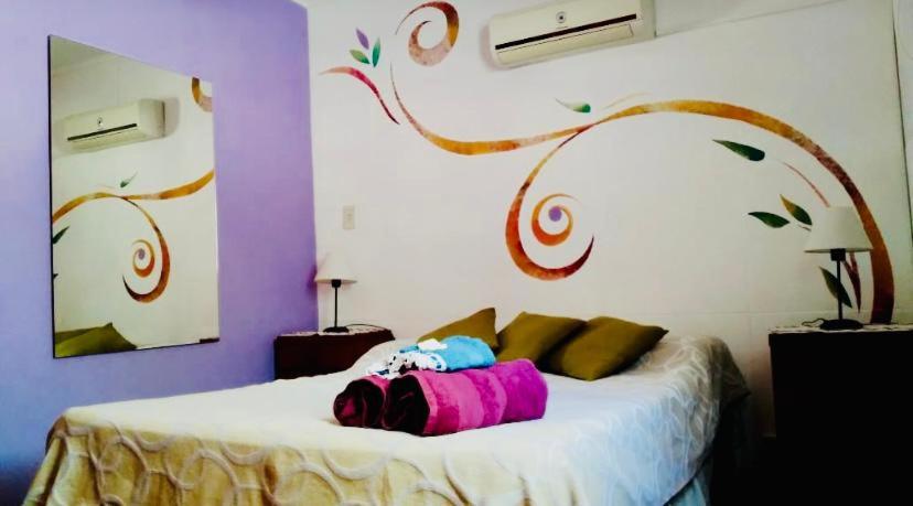 sypialnia z dużym łóżkiem z malowanym drzewem na ścianie w obiekcie Habitación privada,en Espacio Angeles w mieście San Nicolás de los Arroyos