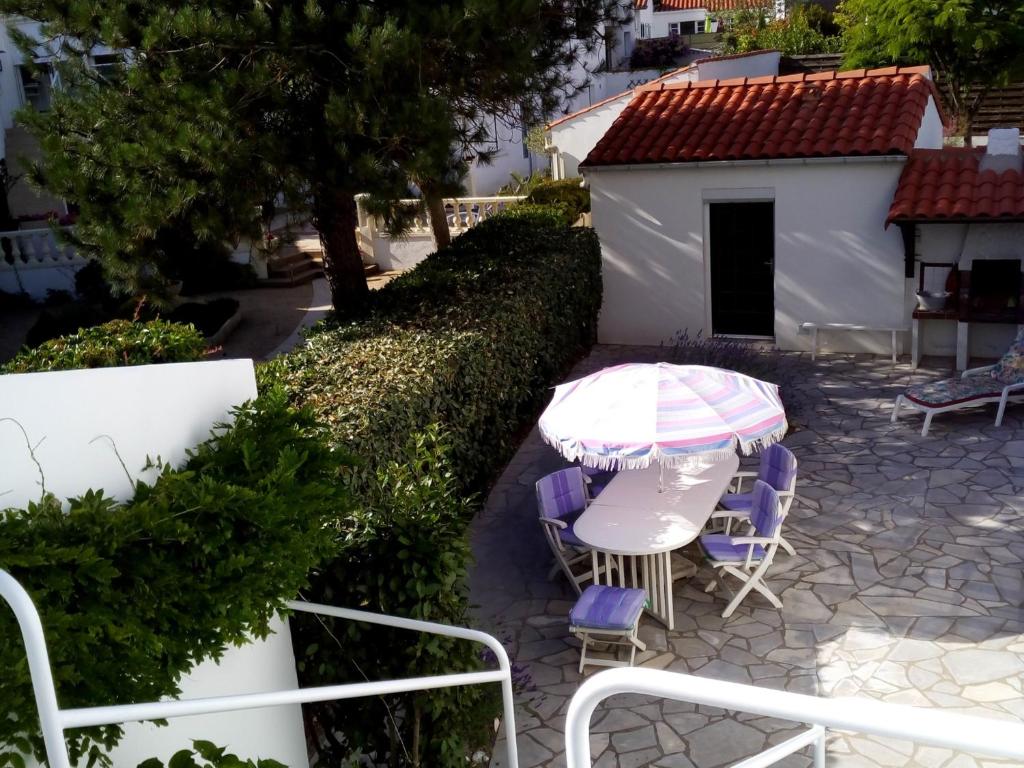 un patio avec une table, des chaises et un parasol dans l'établissement Maison familiale près de la plage, commerces et centre-ville - FR-1-22-202, à La Tranche-sur-Mer