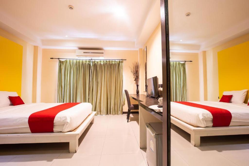 a hotel room with two beds and a mirror at The Main Event in Pattaya South