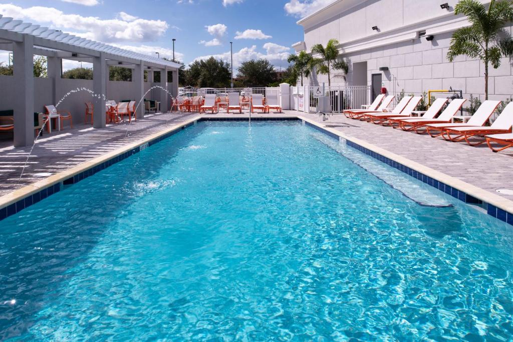 a large swimming pool with chairs and a building at Holiday Inn & Suites Orlando - I-Drive - Theme Parks by IHG in Orlando