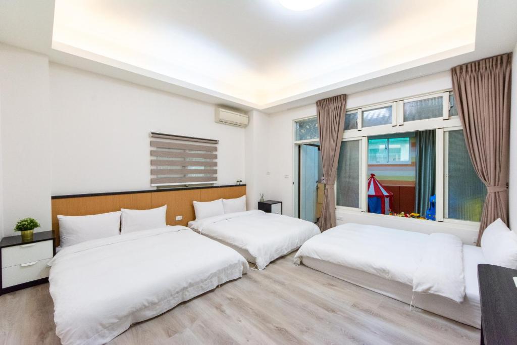 two beds in a room with two windows at 向晴民宿 花蓮市包棟民宿 in Hualien City