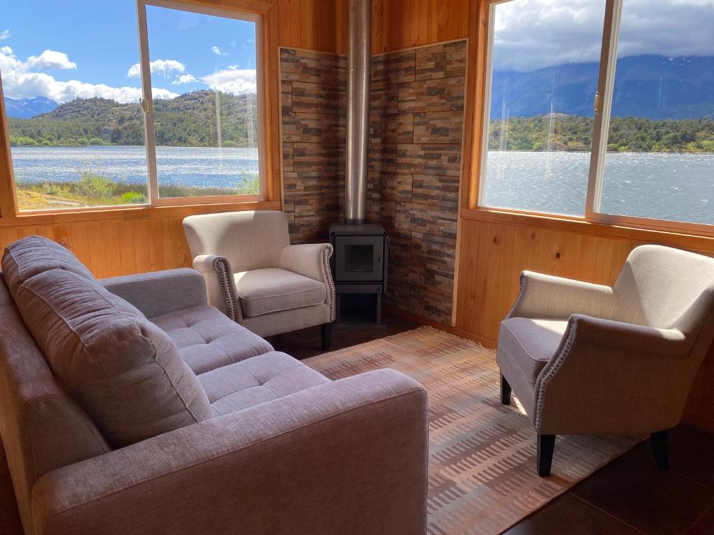 sala de estar con sofá, 2 sillas y ventanas en Turismo Vientos del Sur, en Mallin Grande