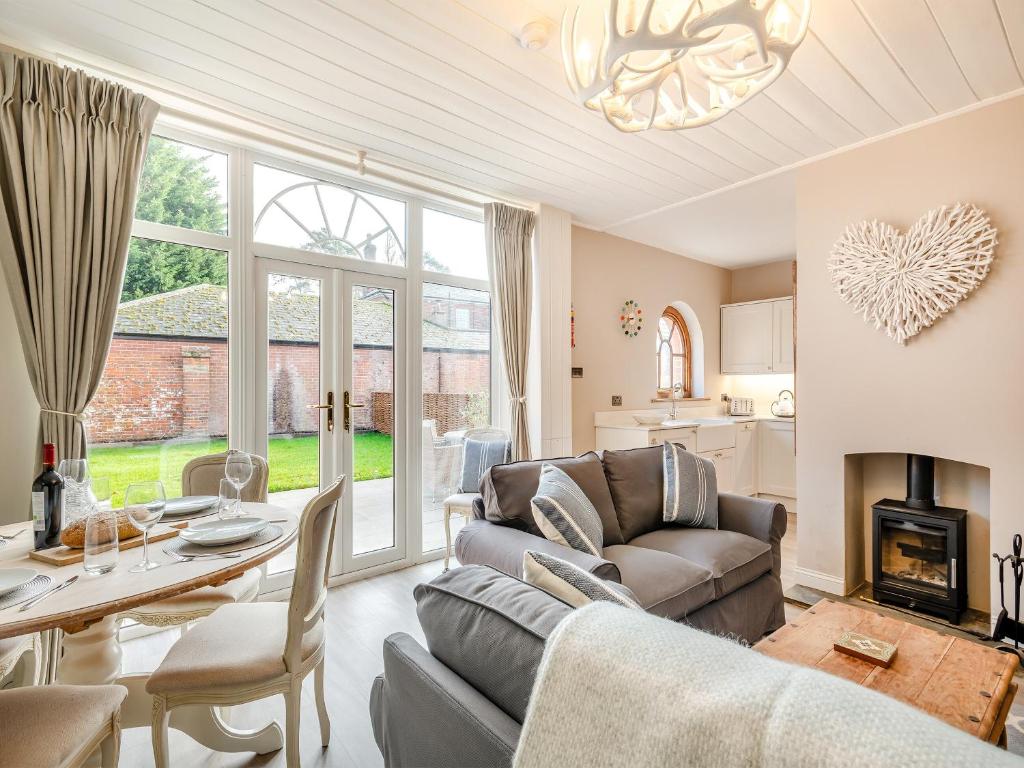 ein Wohnzimmer mit einem Sofa und einem Tisch in der Unterkunft Norfolk Cottages - The Ostlery in Smallburgh