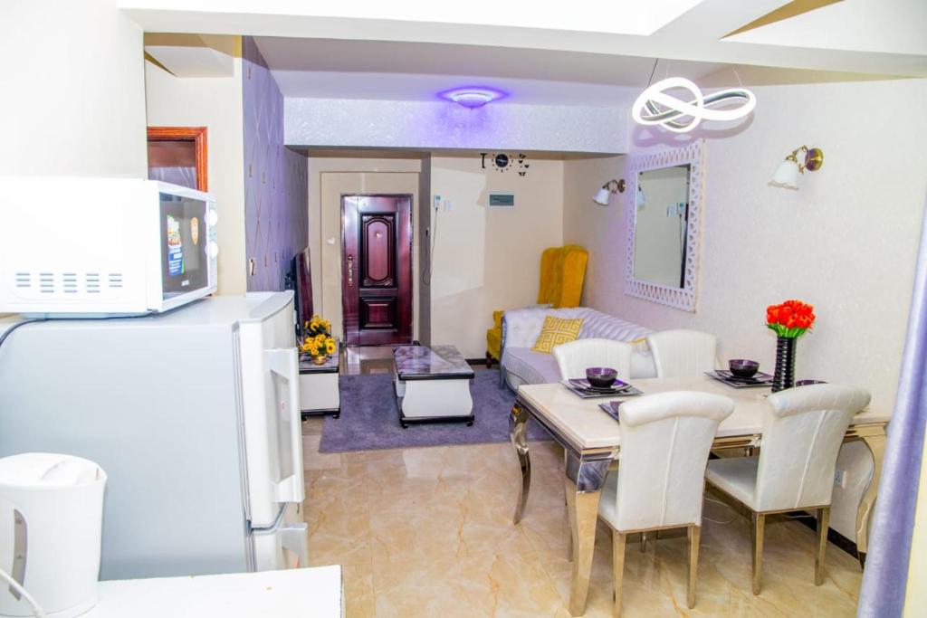 Il comprend une cuisine et un salon avec une table et un canapé. dans l'établissement Lux Suites Marcus Garden Apartments kilimani, à Nairobi