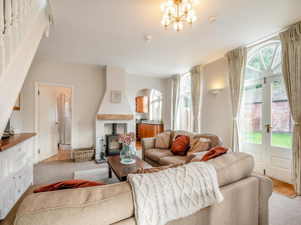 a living room with a couch and a fireplace at Norfolk Cottages - The Coach House in Smallburgh