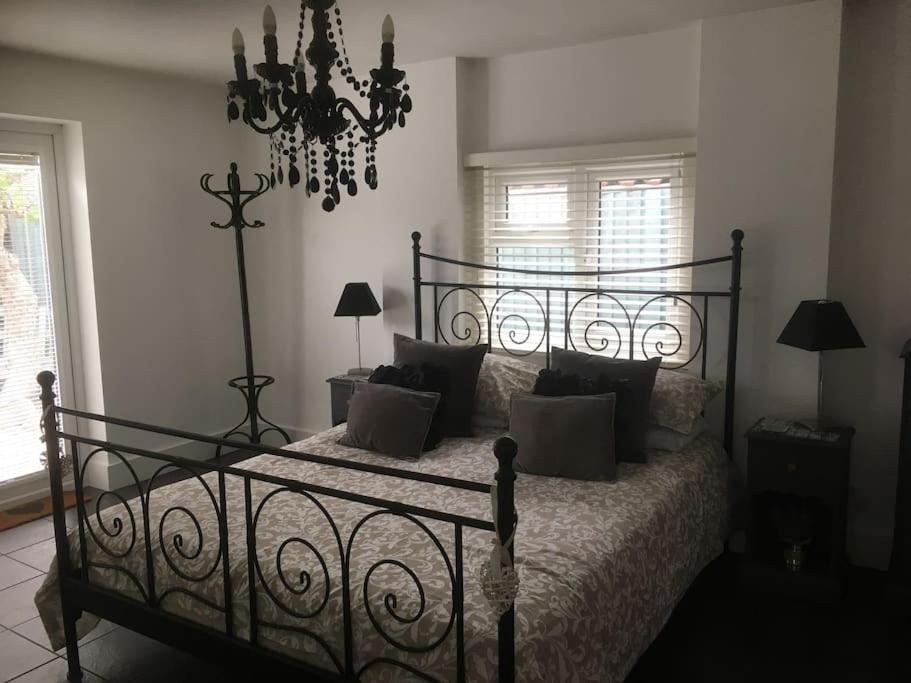 Schlafzimmer mit einem schwarzen Bett und einem Kronleuchter in der Unterkunft Herb Garden Bungalow in Nazeing