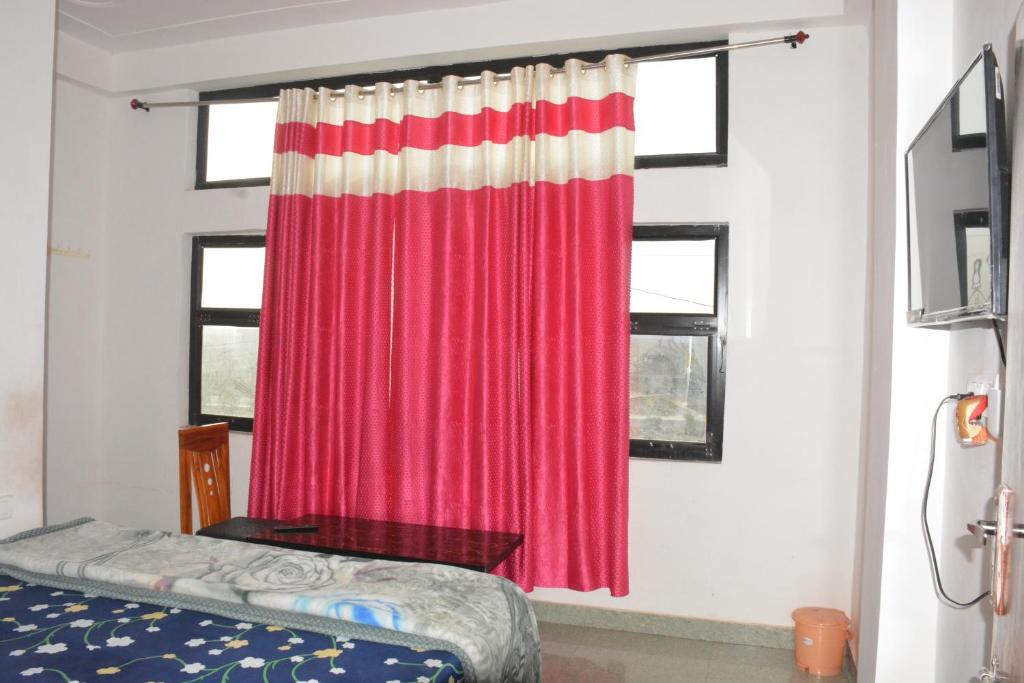 a bedroom with a red curtain and a bed at Hotel Holiday in Bharatpur