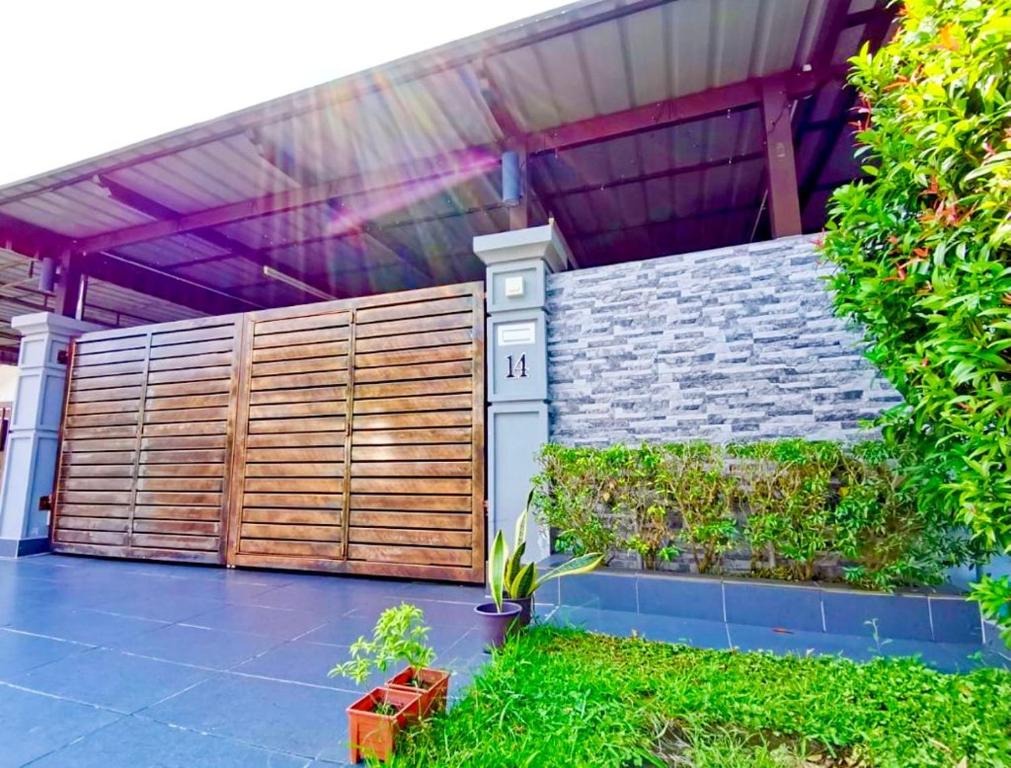 a wooden privacy fence in front of a house at Izzara Iskandar Puteri Homestay Gelang Patah in Gelang Patah