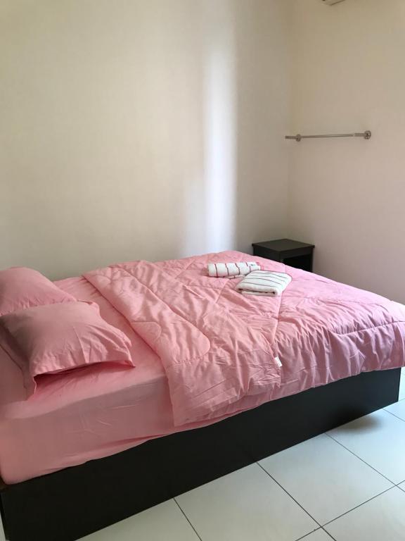 a bed with a pink comforter and pillows on it at Intanova Hotel in Teluk Intan