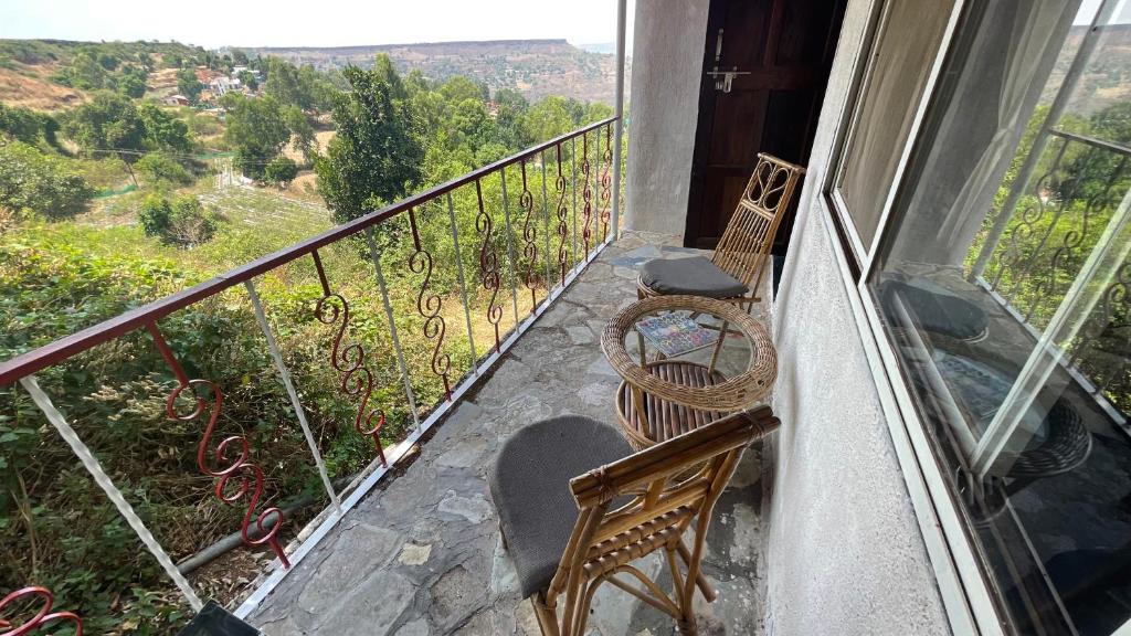 balcón con 2 sillas de mimbre y ventana en Tabletop Villa Balcony - valley view with massive hall, en Panchgani