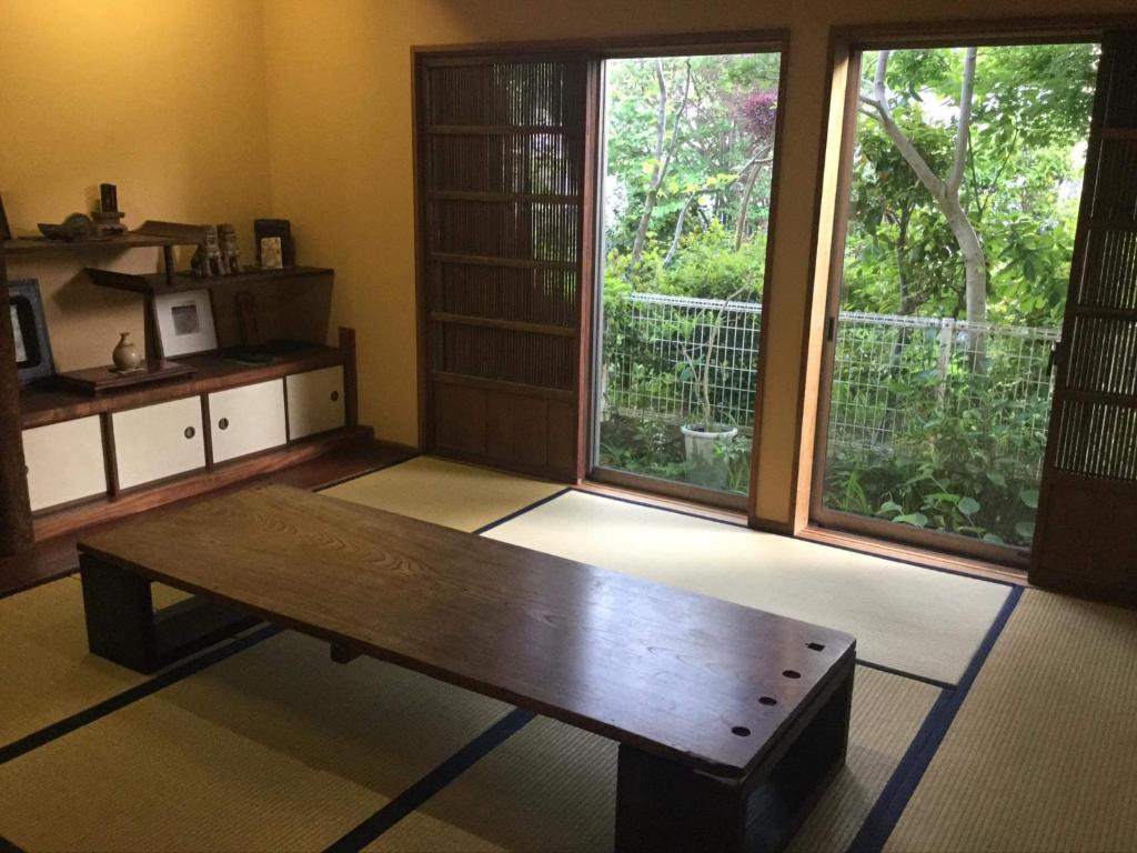 a living room with a wooden table and large windows at 一客一亭の宿 遊楽 in Satsumasendai