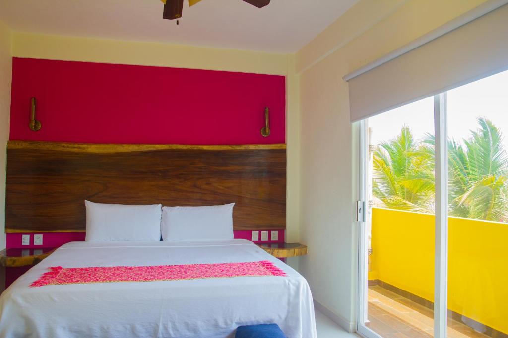 een slaapkamer met een bed met een rode en gele muur bij Hotel Happy Beach in Zihuatanejo