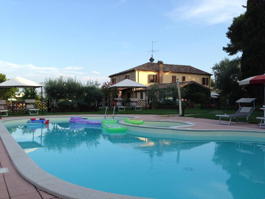 a large swimming pool with a house in the background at Agriturismo Papaveri e Papere in Saludecio