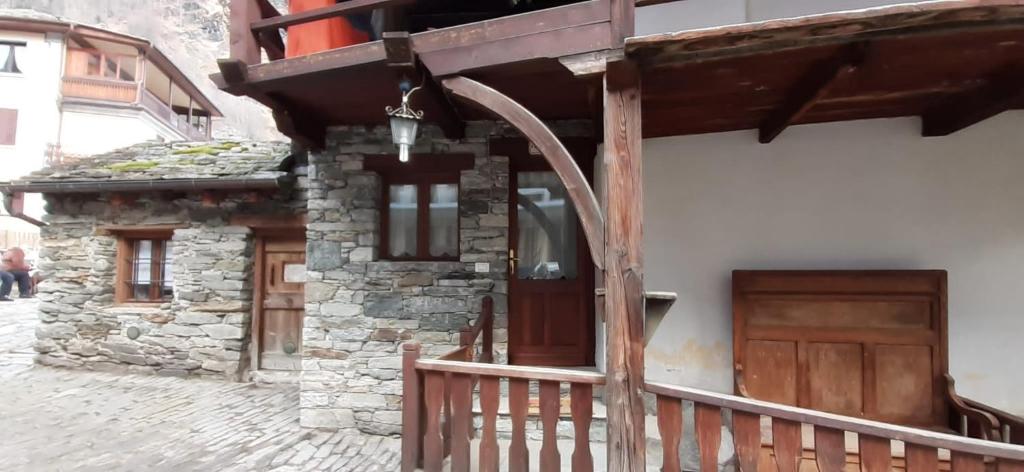 a stone building with a wooden door and a porch at Da Ivana in Alagna Valsesia