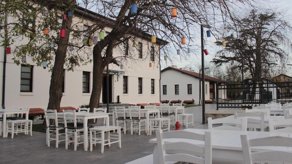 un grupo de mesas y sillas blancas frente a un edificio en İstasyon Otel 