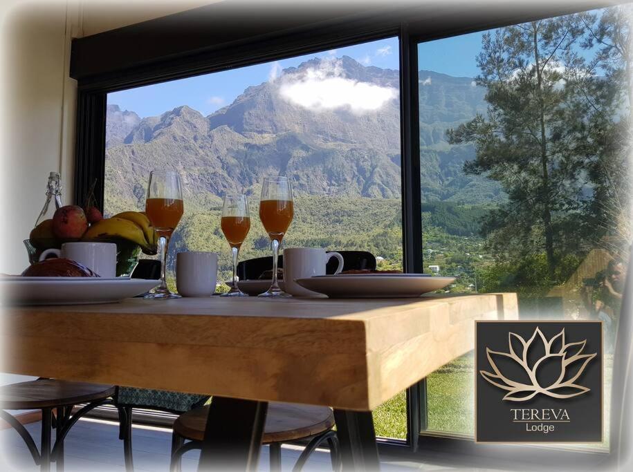 una mesa con copas de vino y vistas a la montaña en Téréva Lodge - La villa de standing, en Cilaos