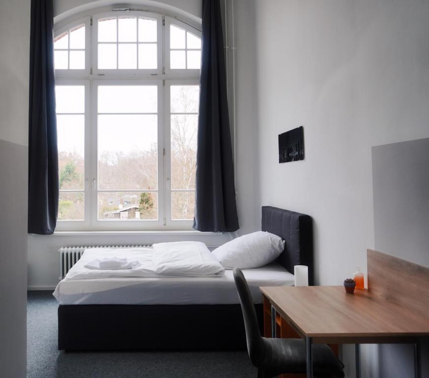 a bedroom with a bed and a window and a table at Motel Home Wittenau in Berlin