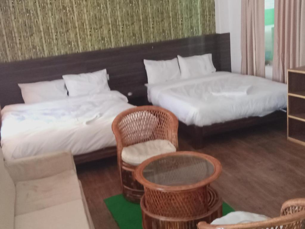 una camera da letto con due letti, un tavolo e delle sedie di Everest Guest House a Pokhara