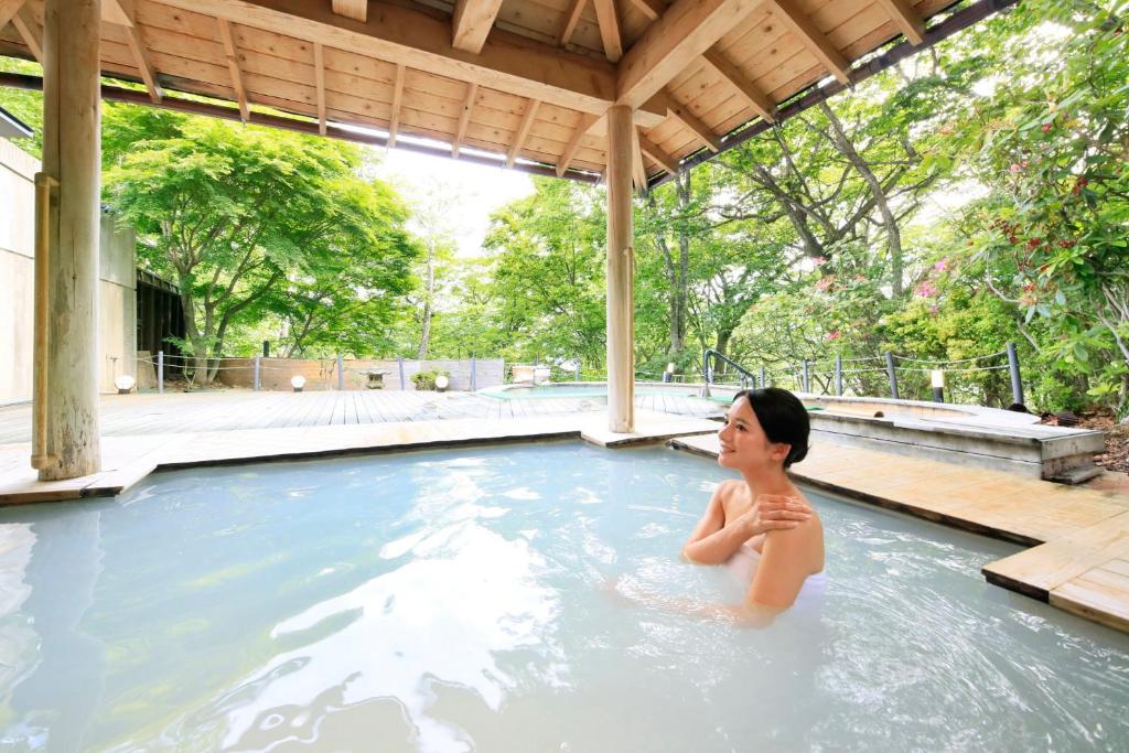 a woman sitting in a swimming pool at Hotel Shikisai in Nikko