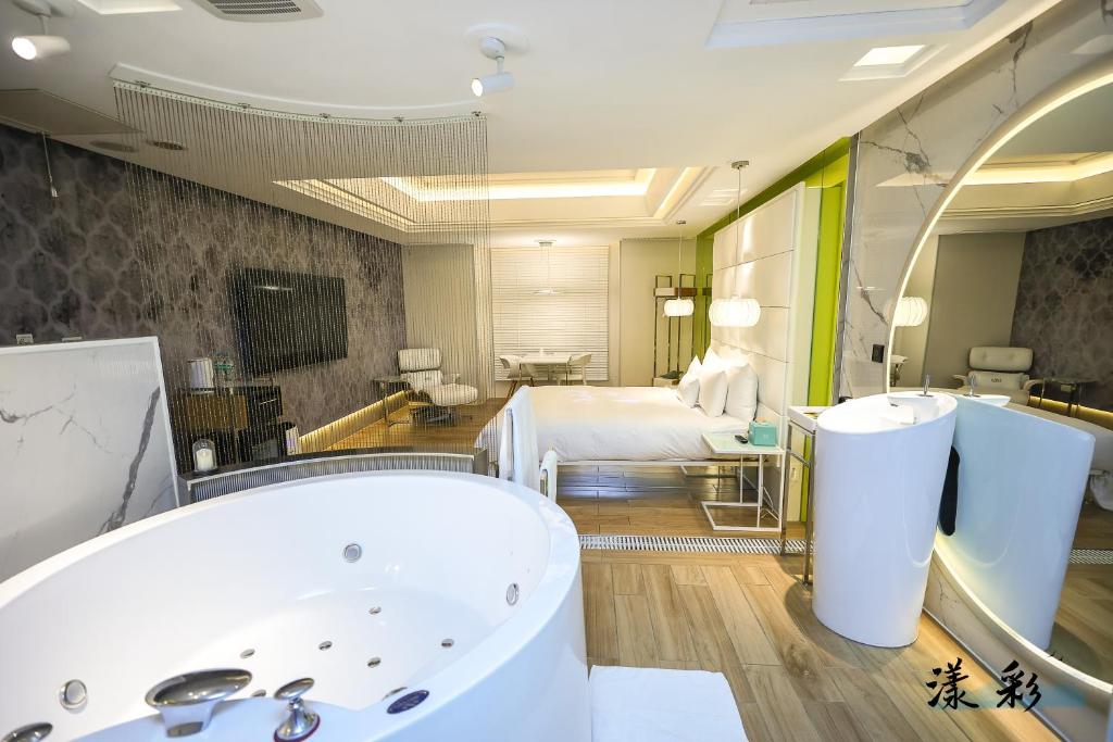 a bathroom with a tub and a bed in a room at MMMotel in Taoyuan