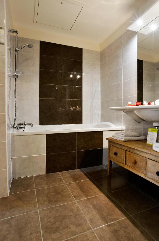 a bathroom with a bath tub and a sink at Almoria Hôtel & SPA in Deauville