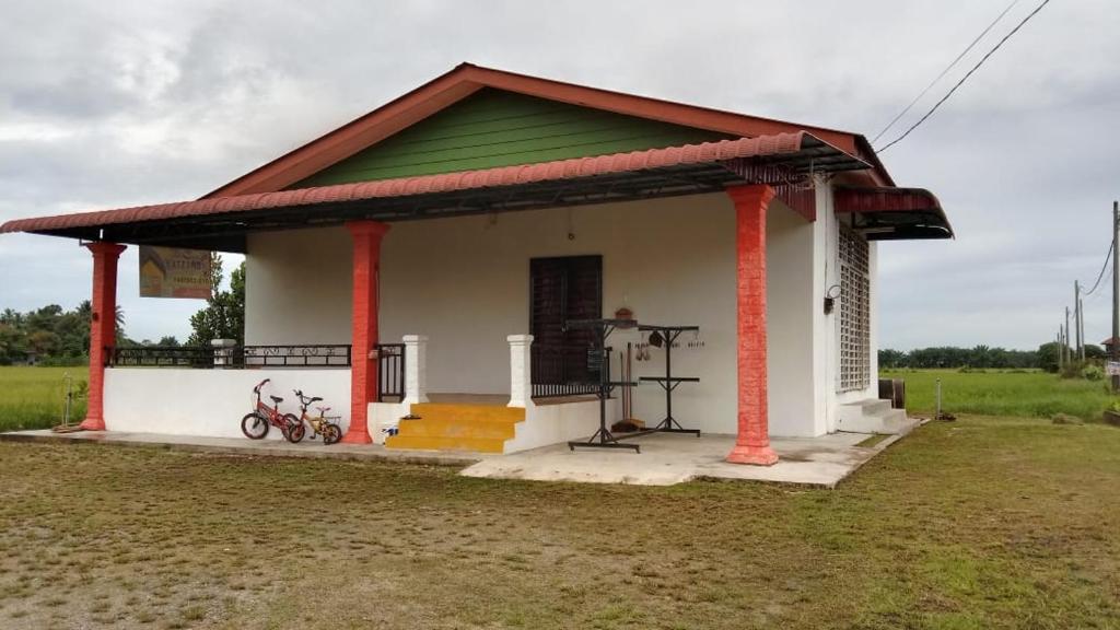 uma pequena casa branca com um telhado verde em Sobey Laris Homestay KAYDEE em Pasir Mas