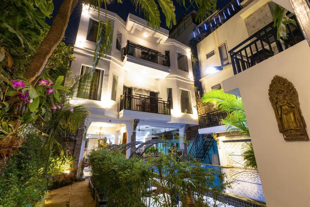 a large white building with a courtyard at night at The Five Senses Boutique Hotel in Siem Reap