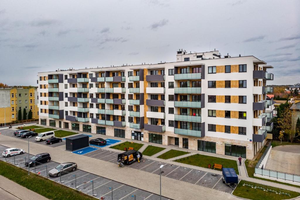 un grande edificio bianco con auto parcheggiate in un parcheggio di Apartments 24h a Varsavia