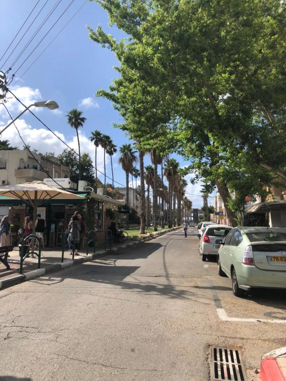 une rue avec des voitures garées sur le côté de la route dans l'établissement Bat Galim - by the sea, à Haïfa