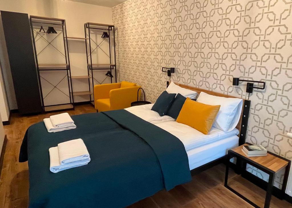 a bedroom with a large bed and a yellow chair at PM. Apartments Krakow in Kraków