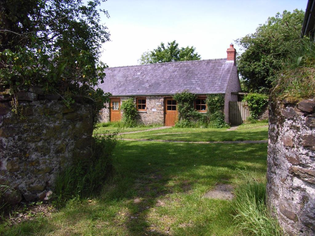 una vieja casa de piedra con una pared de piedra delante de ella en Long barn, en Kilgetty