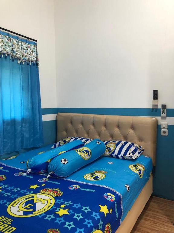 a bed with blue comforter and pillows on it at PENGINAPAN BANYU BIRUKu in Kota-anyar