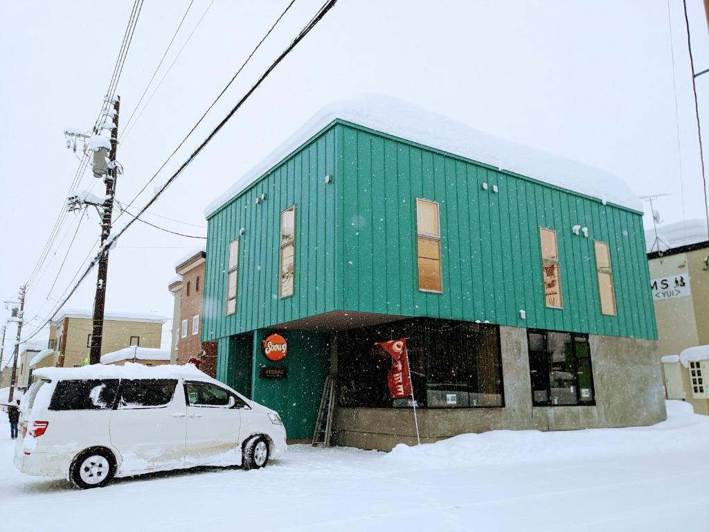 倶知安町にあるTboxの緑の建物の前に停車する白いバン