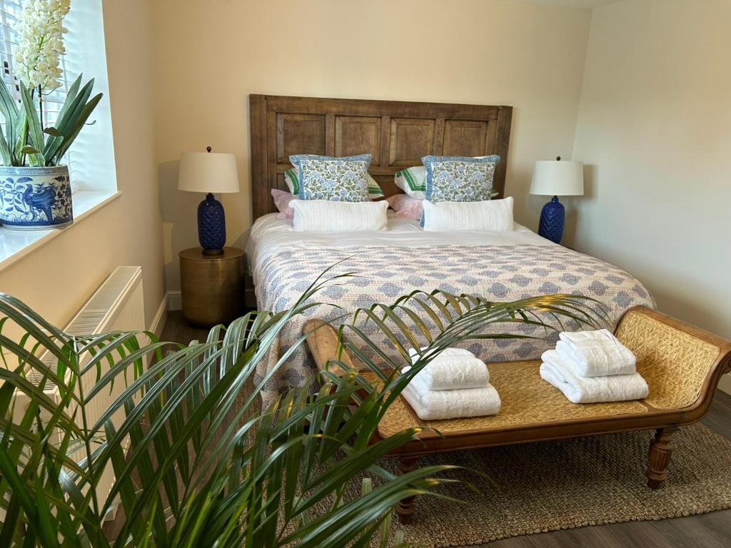 a bedroom with a bed with towels on a bench at The Pelican Room-converted Cart Lodge near airport in Horsham Saint Faith