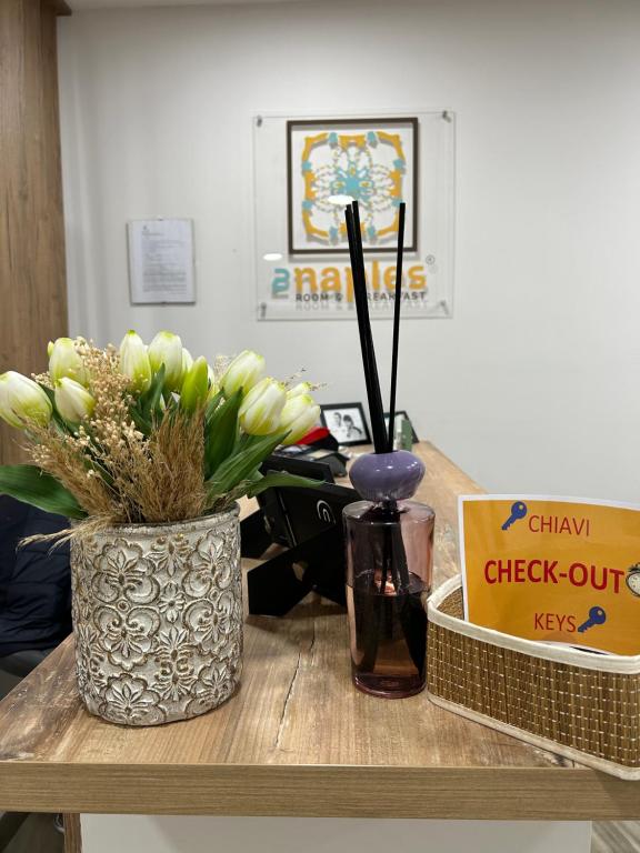 een houten tafel met een vaas met bloemen en een doos bij 2Naples Rooms in Napels