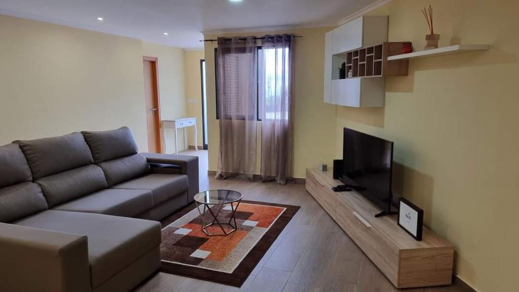 een woonkamer met een bank en een flatscreen-tv bij Lombada House in Ponta Delgada