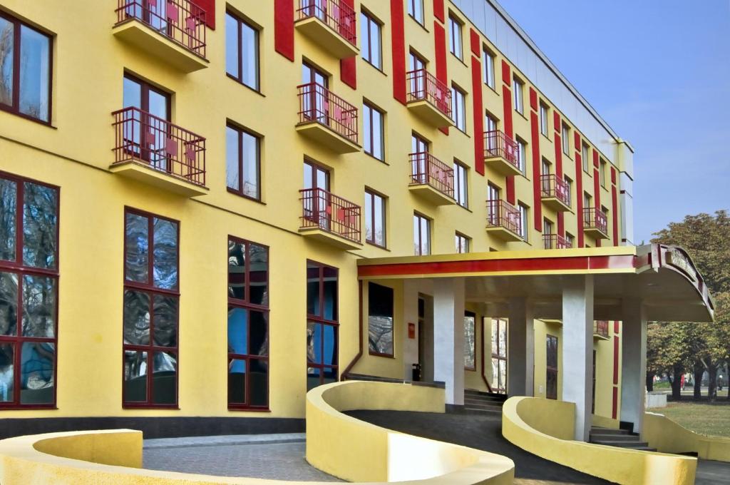 un edificio amarillo con sillas delante en Optima Deluxe Kryvyi Rih, en Krivoy Rog