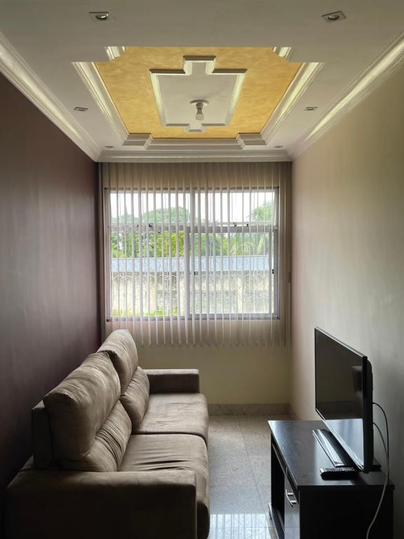 een woonkamer met een bank en een tv bij apartamento completo in Contagem