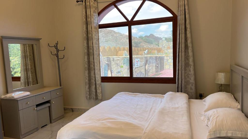 a bedroom with a bed and a large window at Sunrise Farm استراحة مطلع الشمس in Hatta