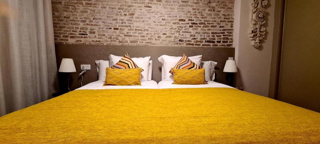 una camera da letto con un grande letto con lenzuola e cuscini gialli di Apartamento Viña P. Málaga Centro a Málaga