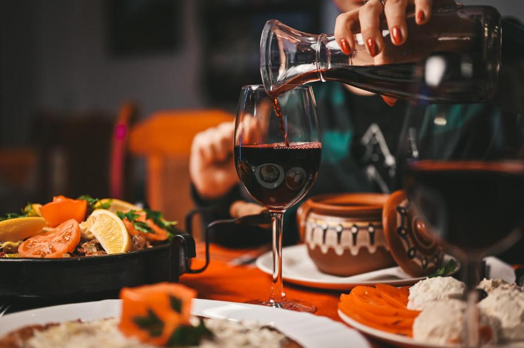une personne versant du vin rouge dans un verre sur une table dans l'établissement Хотел Феникс, à Chepelare