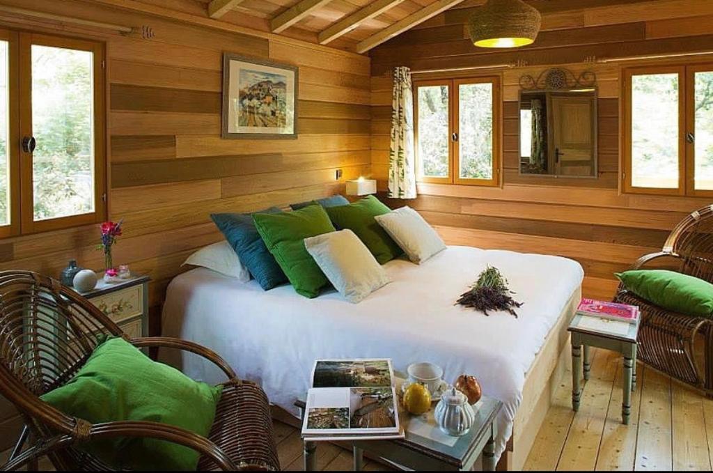 um quarto com uma cama grande e almofadas verdes em La Bastide Du Bois Breant em Maubec